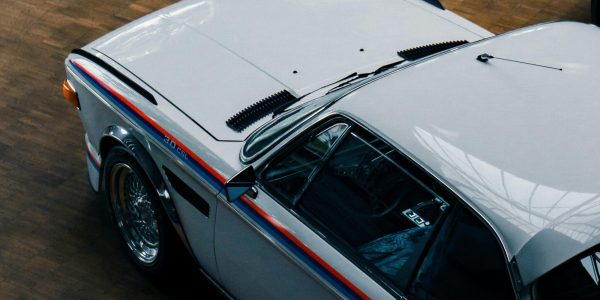 Top view of a vintage white classic car showcased indoors on a wooden floor.